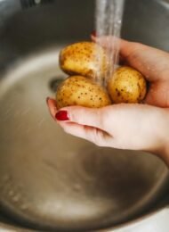 Frau wäscht Kartoffeln, die resistente Stärke enthalten