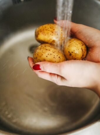 Frau wäscht Kartoffeln, die resistente Stärke enthalten